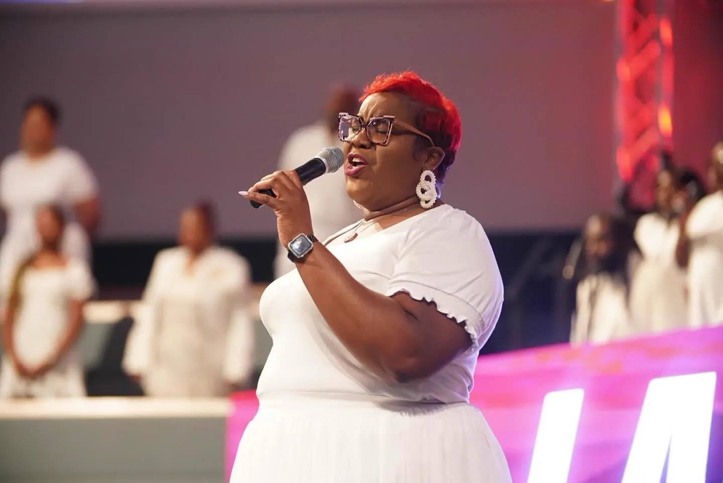 Worship leader singing with the choir behind her