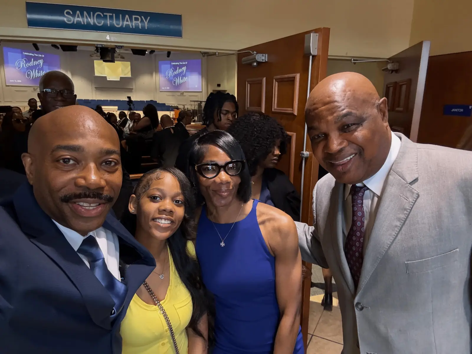 Pastor smiling with church members in the sanctuary doorway