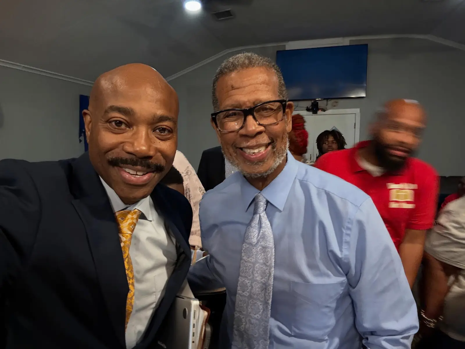 Pastor posing with a church member for a selfie indoors