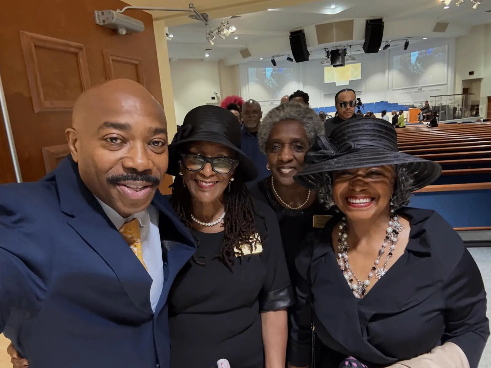 Pastor smiling in a group selfie with church mothers inside the sanctuary