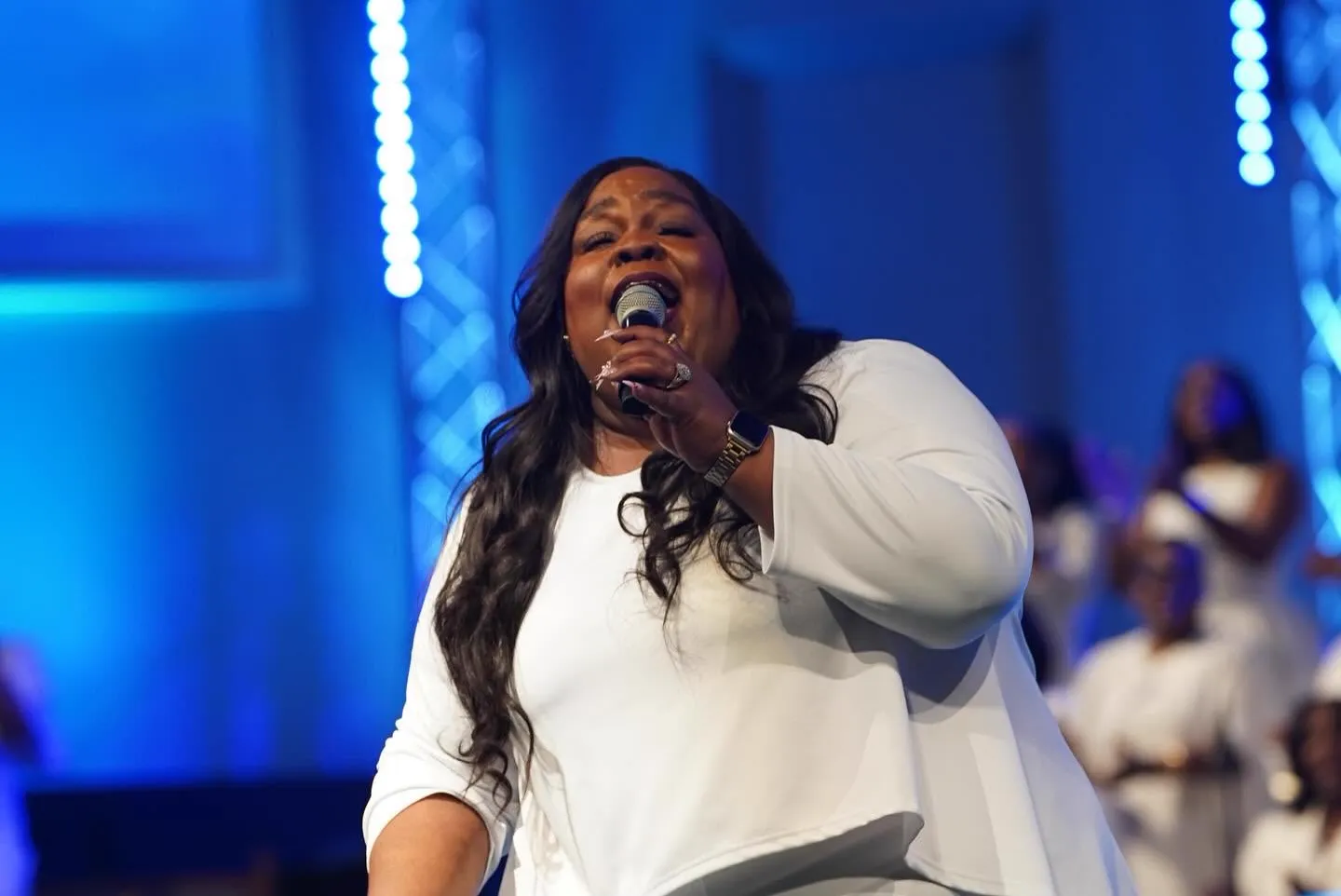 Worship leader singing on stage in blue light